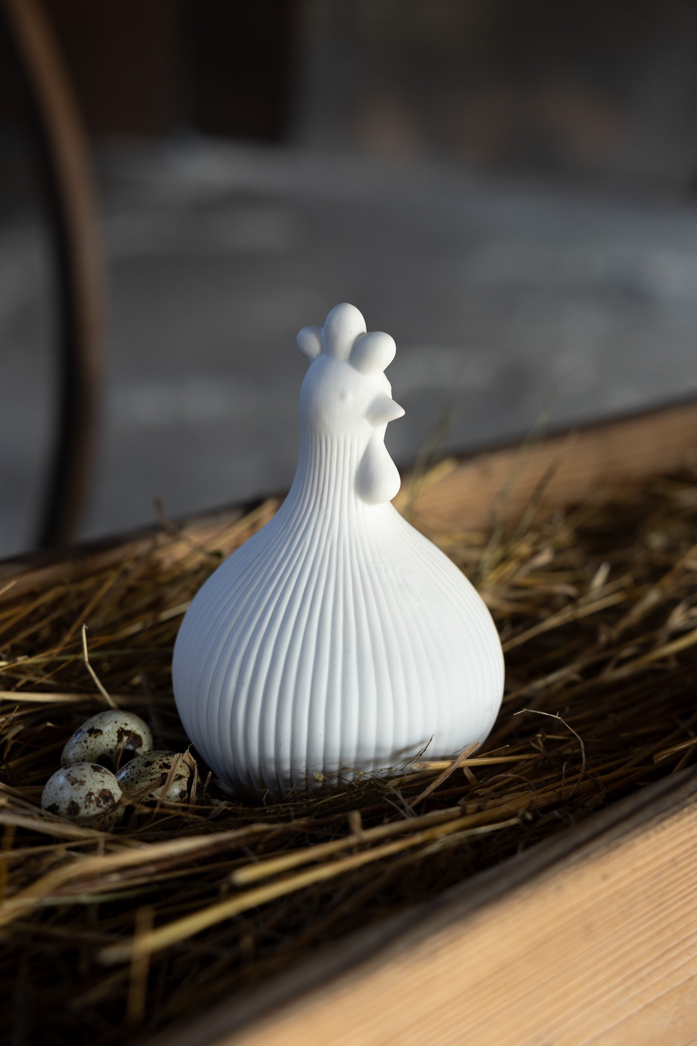 Die unglasierte Keramik verleiht dem Huhn eine edle, kalkartige Haptik und ein sanftes Erscheinungsbild, das das Licht im Raum weich reflektiert.